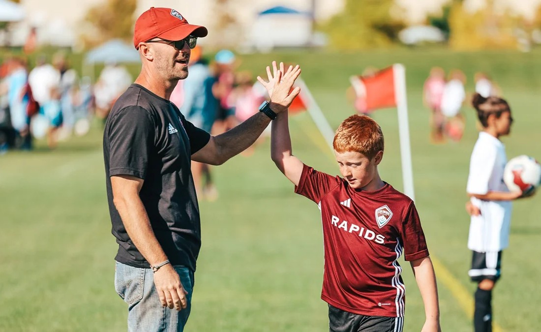A youth soccer player giving a high five to his coach during a game in Colorado