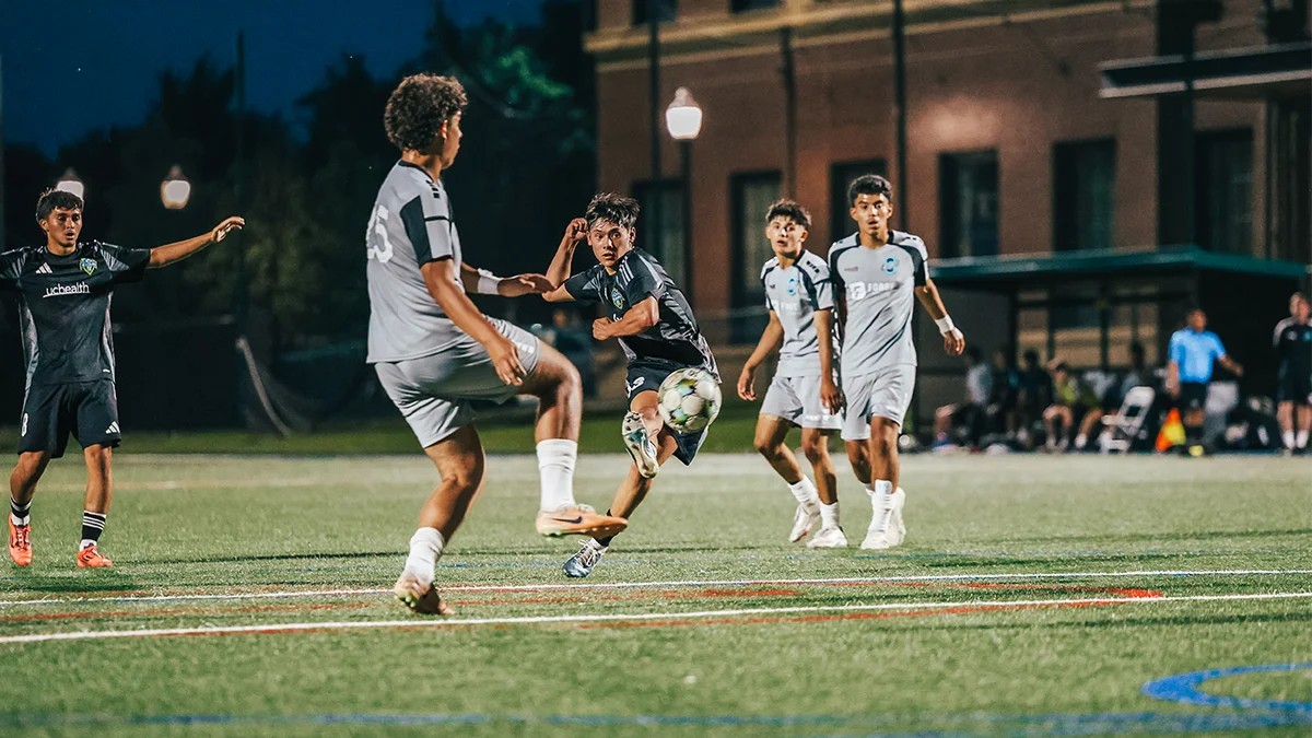 Teenage soccer players competing for the ball during a high intensity match under stadium lights in Denver
