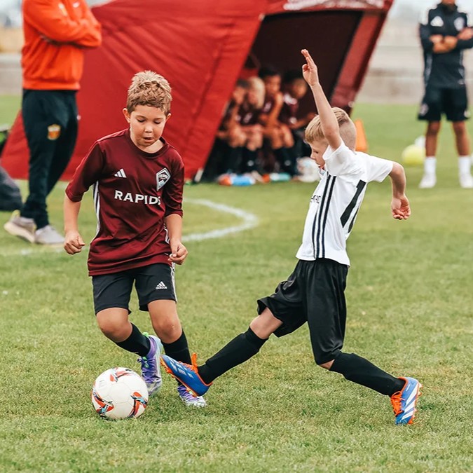 Two youth soccer players competing for the ball during an outdoor match in Colorado