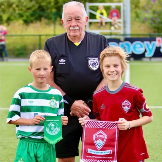 Youth soccer captains from Colorado Storm and Shamrock Rovers exchanging club pennants with a referee