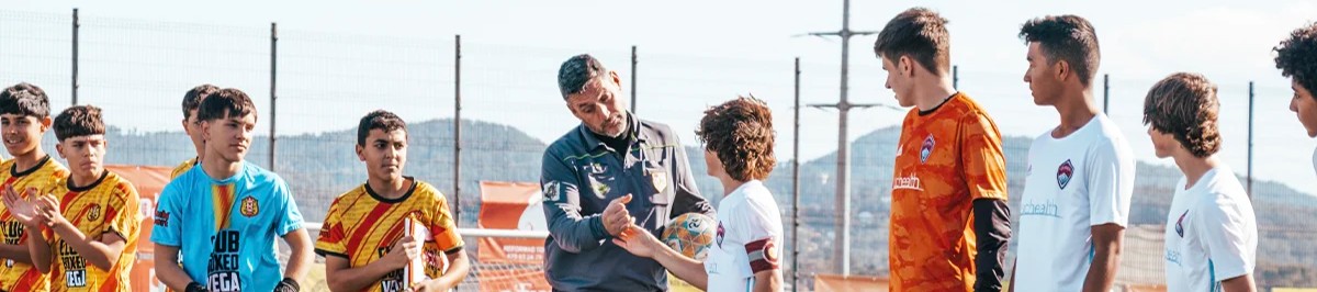 Youth soccer players exchanging a pennant with a referee before a friendly match in Barcelona Spain