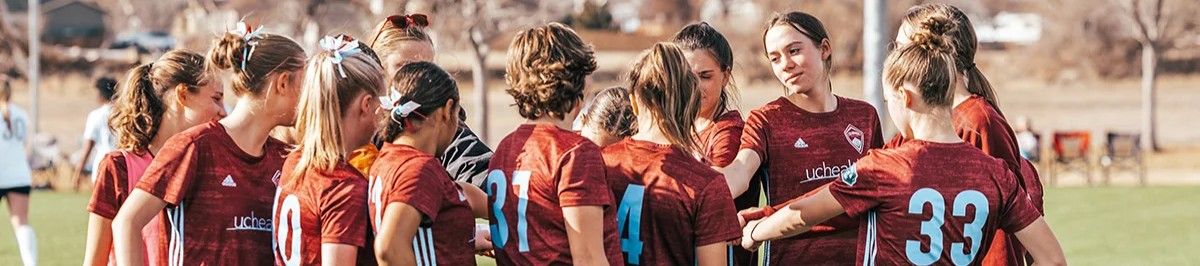 Youth soccer players in a team huddle on a sunny field during a Storm game in Colorado 1