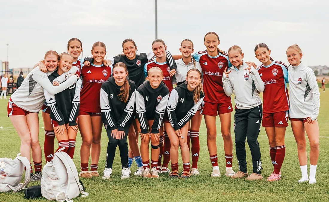 competitive girls soccer team posing on field